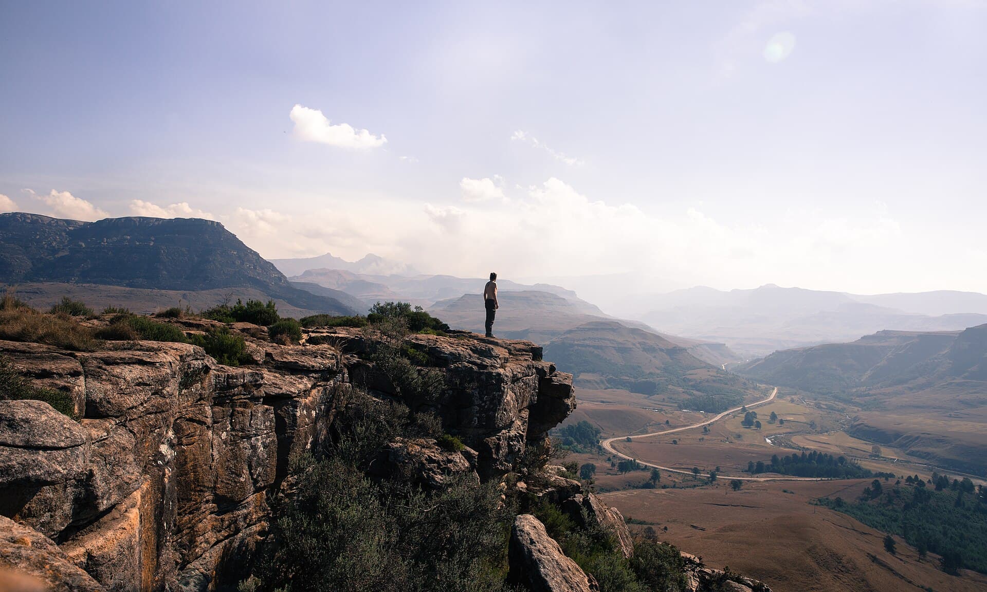 A hiker on a rocky outcrop above the valley at Sani Pass, southern Drakensberg